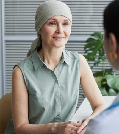 Vertical portrait of smiling mature woman talking to female doctor during consultation in medical clinic