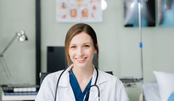 Young female doctor in white medical uniform using laptop and tablet talking video conference call at desk,Doctor sitting at desk and writing a prescription for her patient in hospital